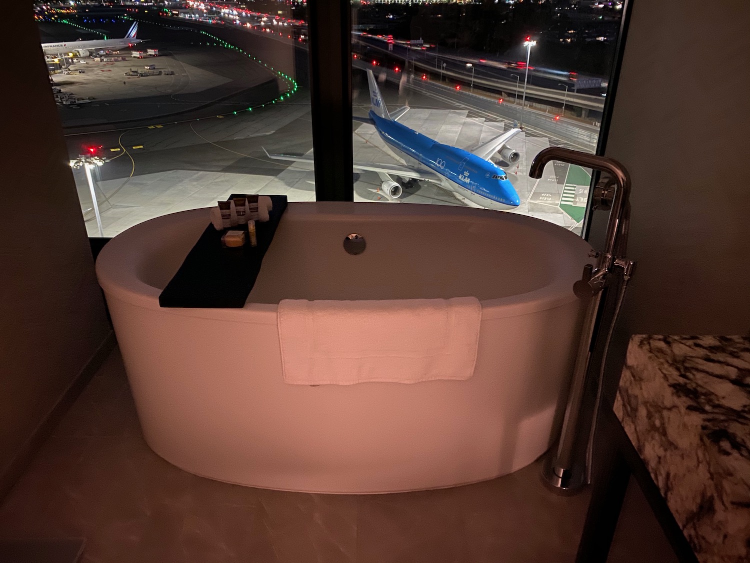 a tub in a room with a window and an airplane in the background