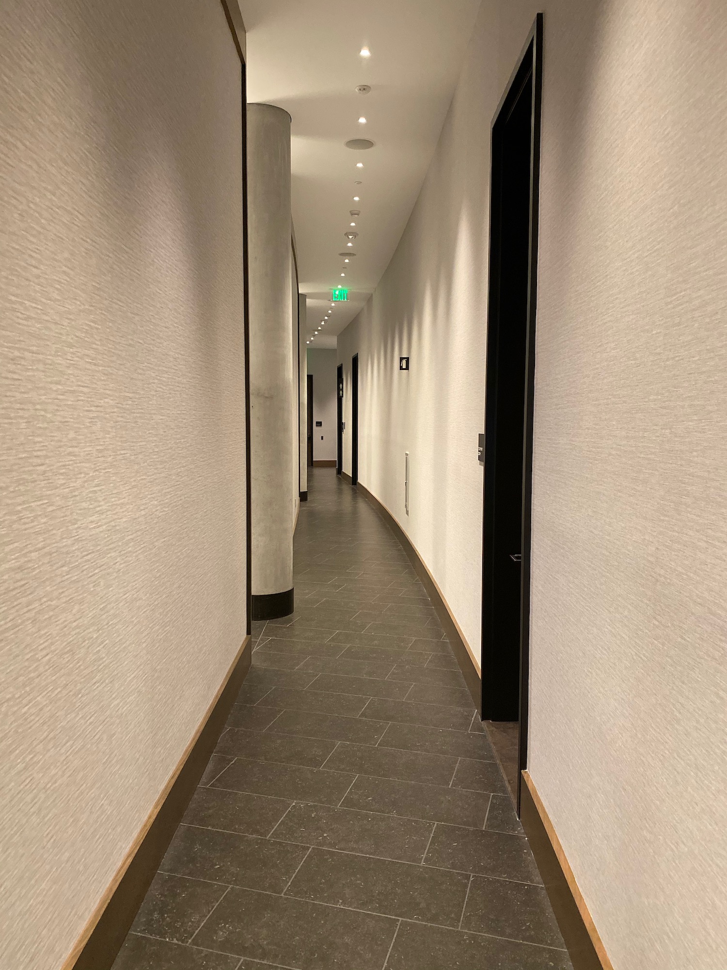 a hallway with white walls and a black door