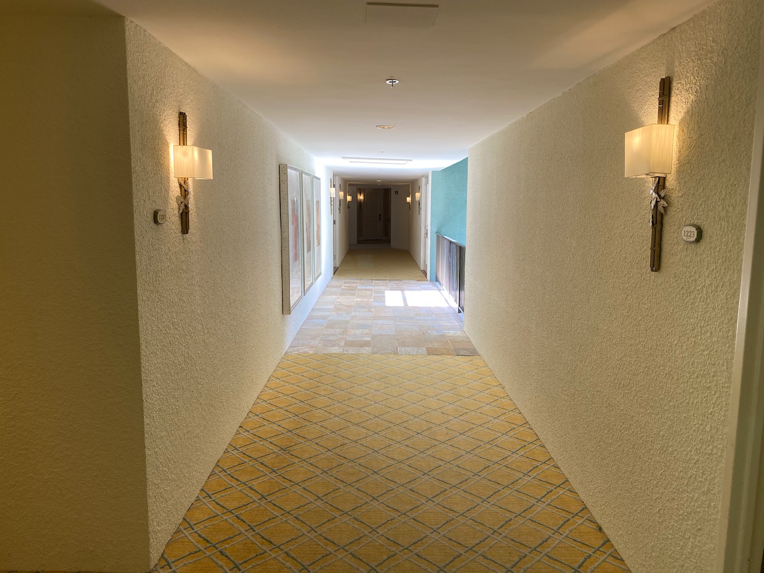 a hallway with sconces and a yellow carpet