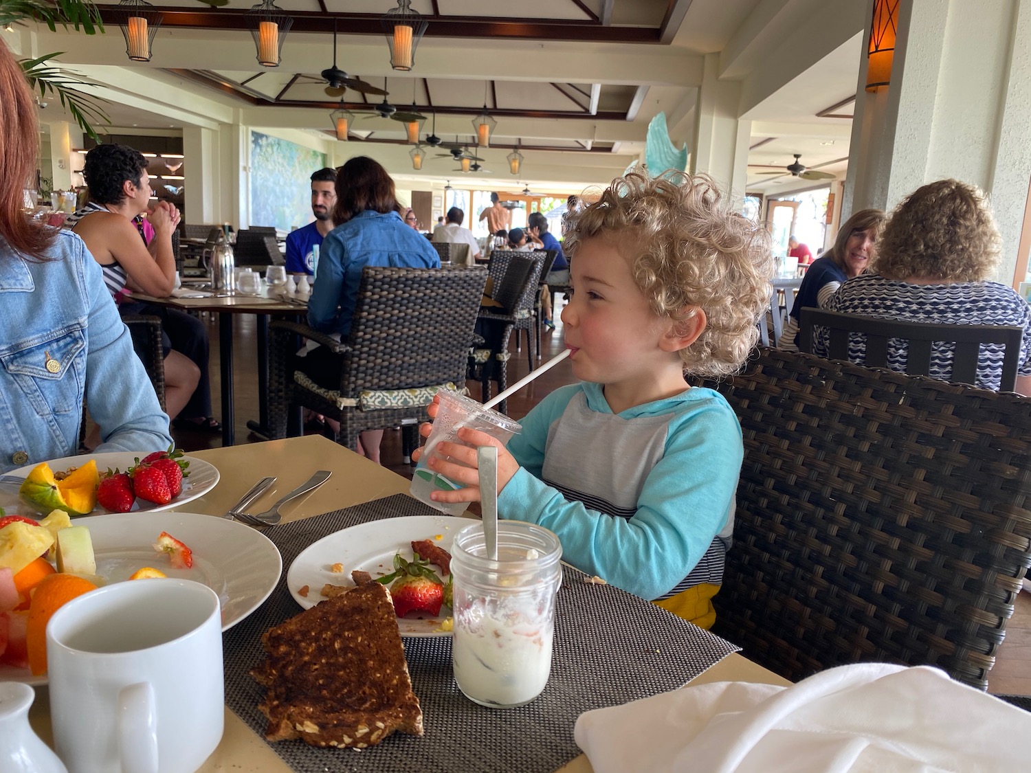 a child drinking from a straw at a table with food