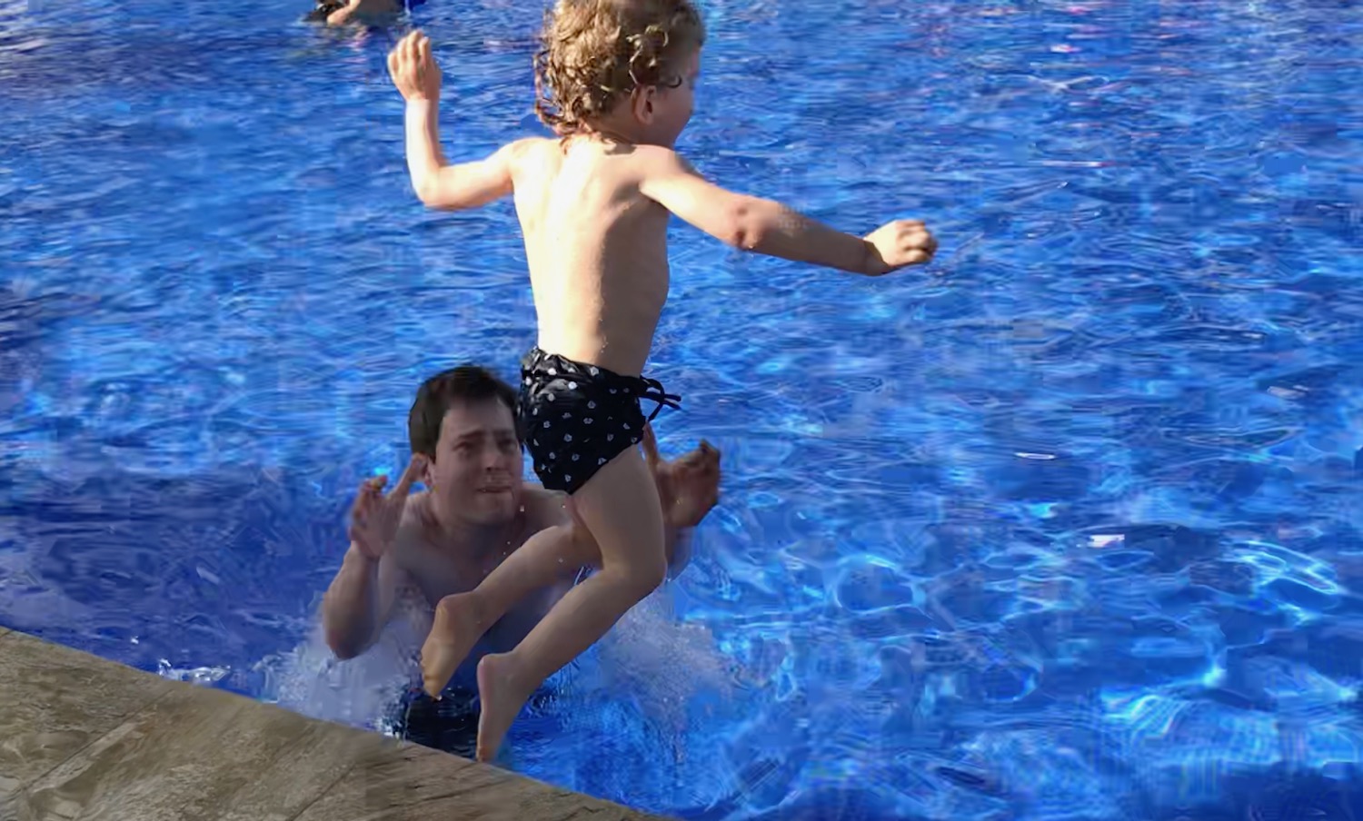 a man and child jumping into a pool