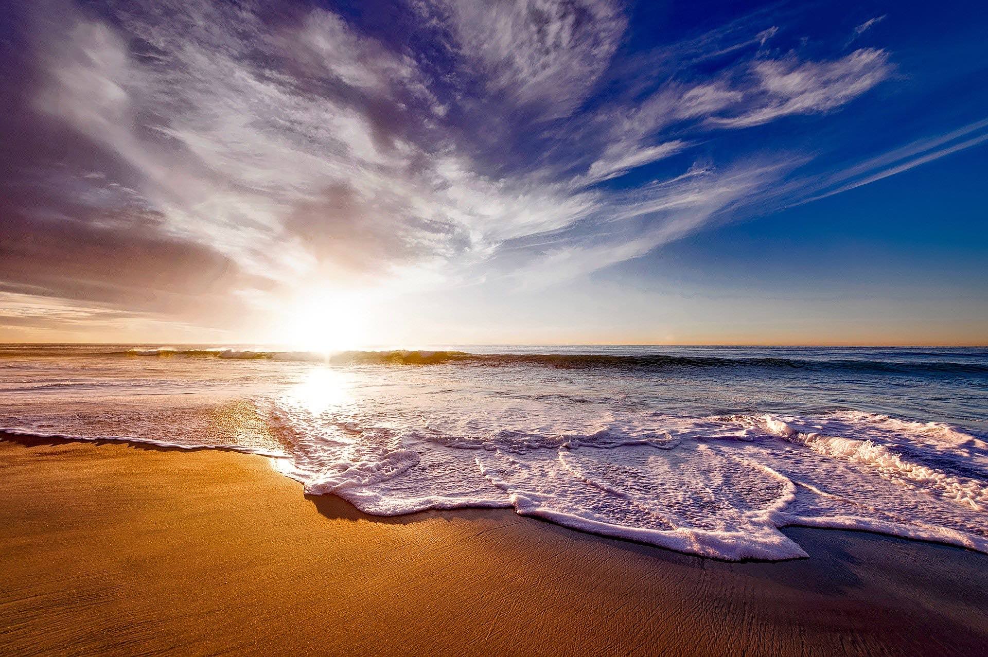 a beach with waves and a sunset