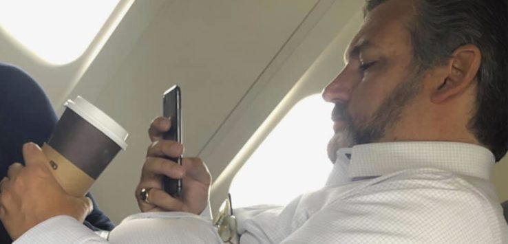 a man sitting on an airplane looking at his phone