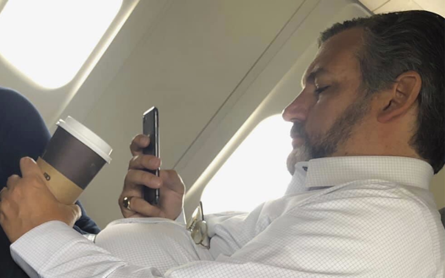a man sitting on an airplane looking at his phone