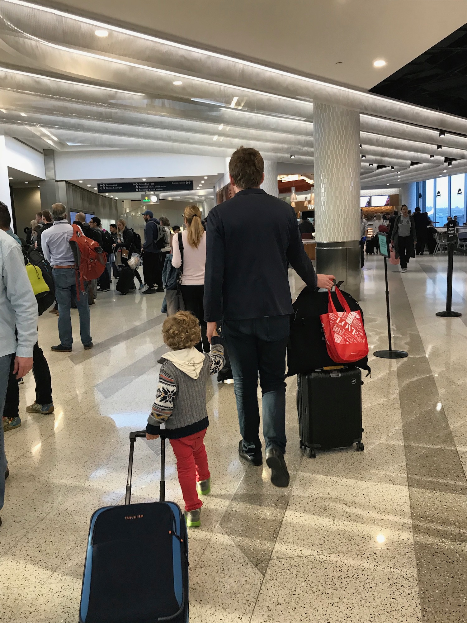 a man and child walking with luggage in an airport