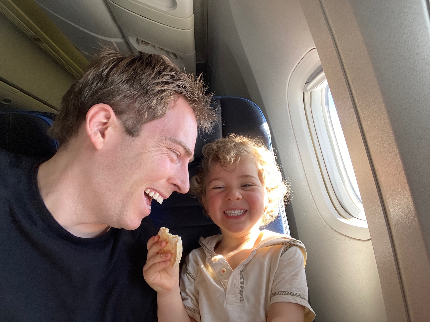 a man and child smiling while sitting in an airplane