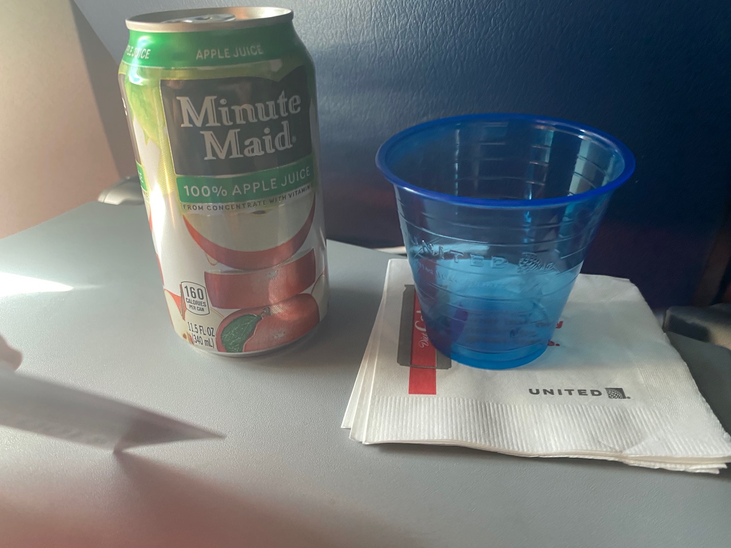 a can of apple juice next to a plastic cup