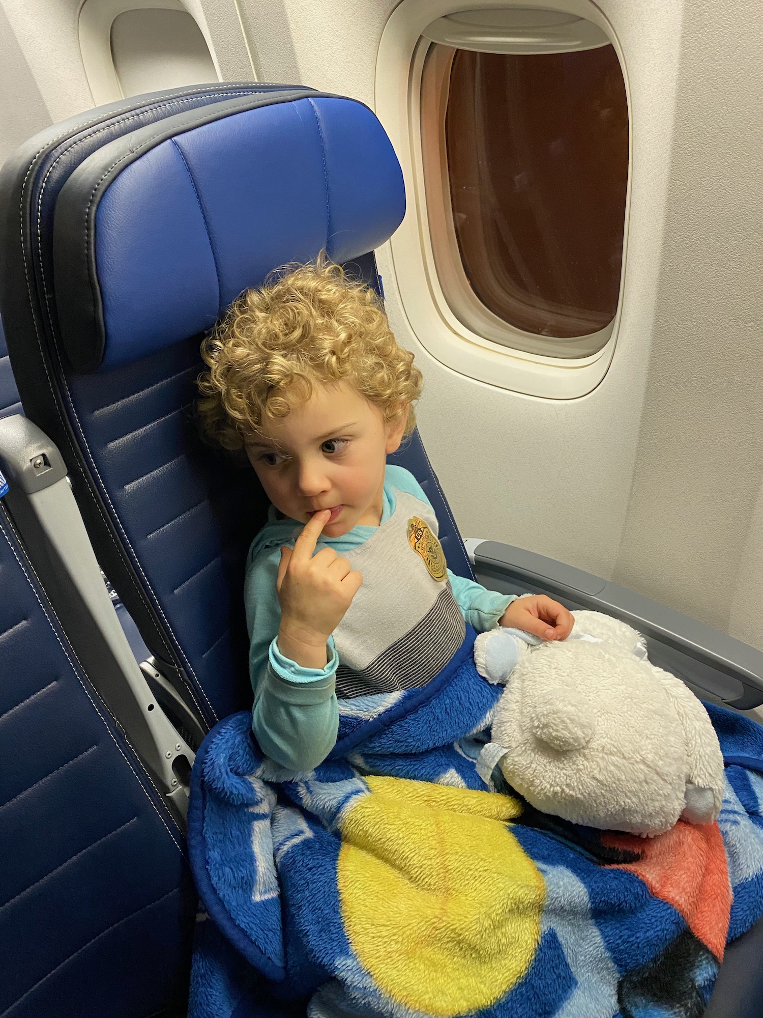 a child sitting in a plane with a stuffed animal