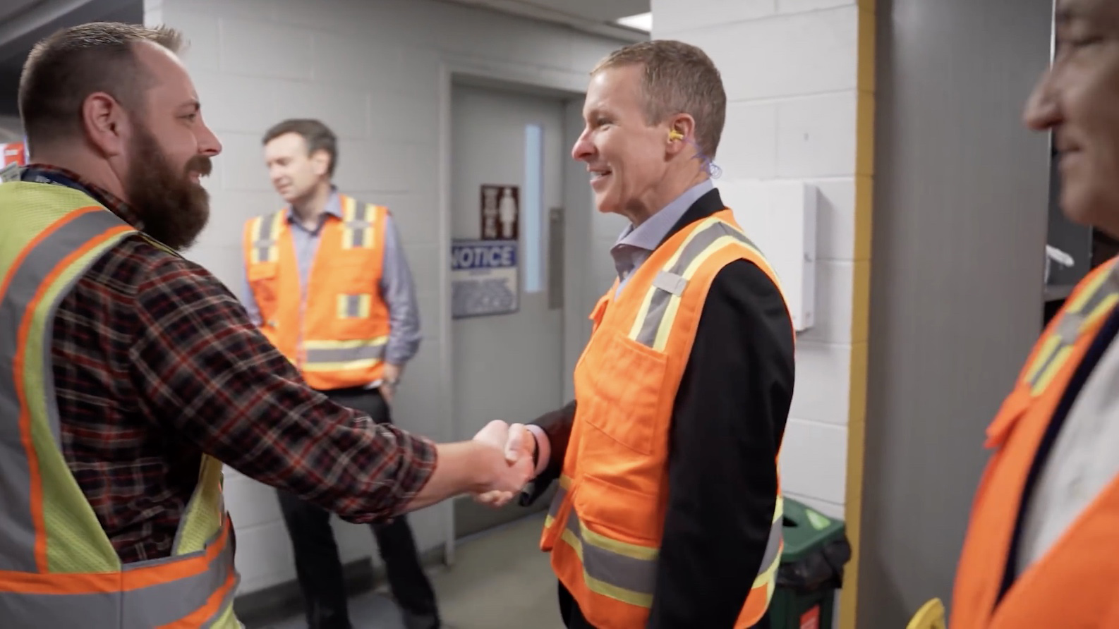a man in safety vest shaking hands with another man in safety vest