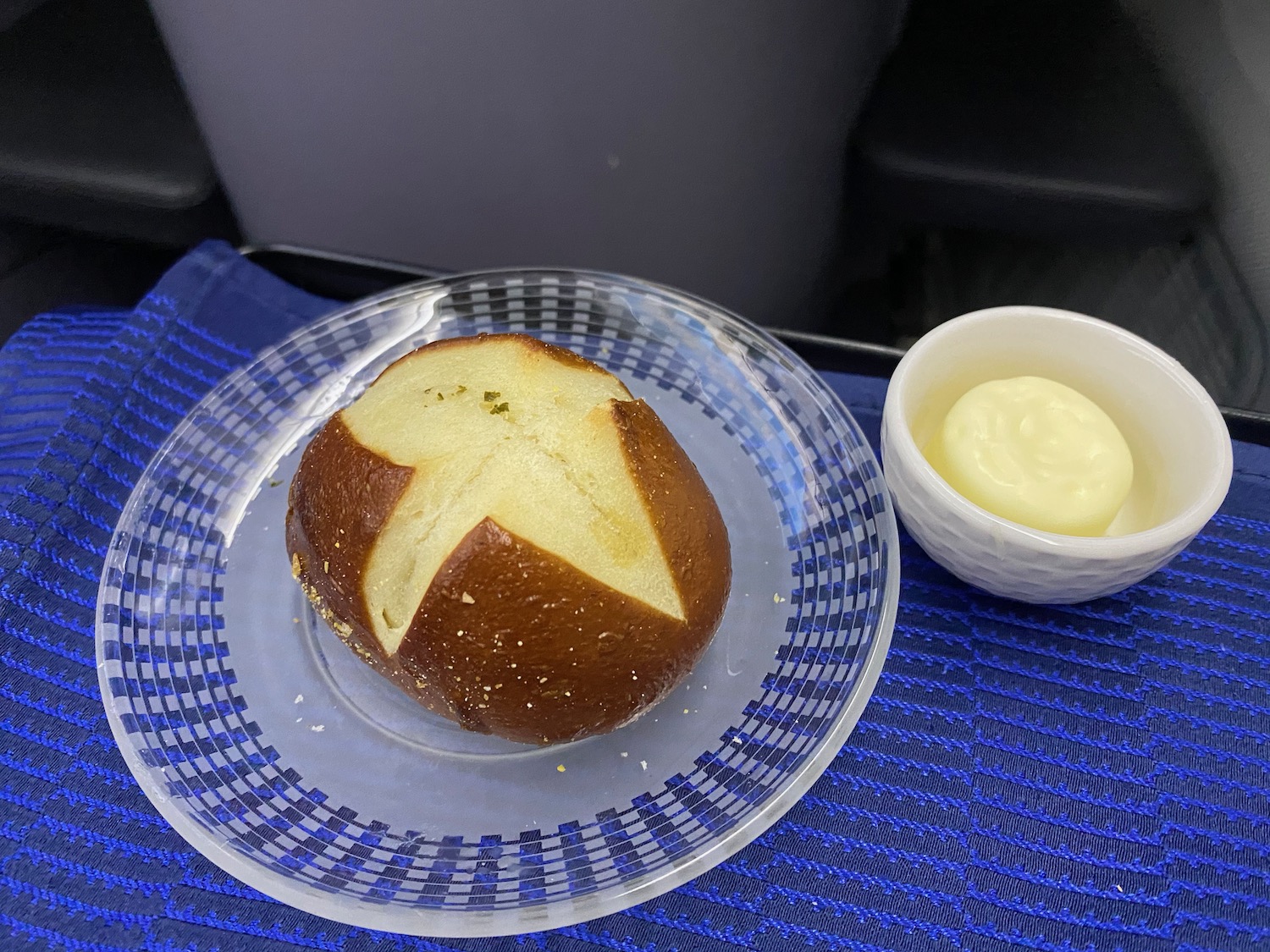 a bread roll on a plate with a small bowl of butter