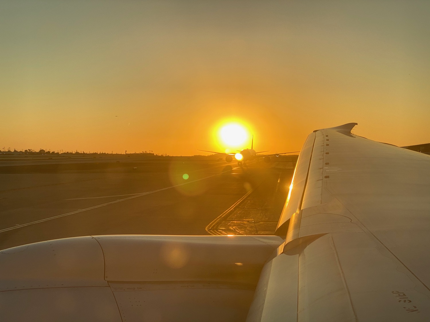 an airplane wing on a runway during sunset