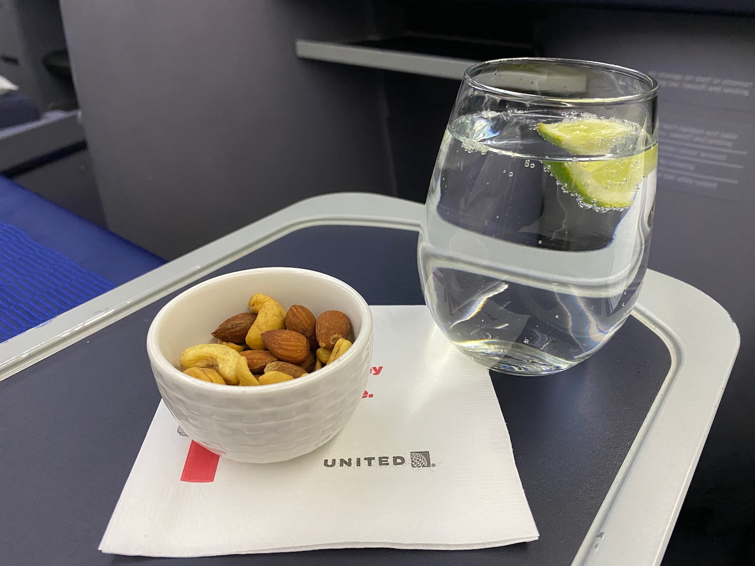 a bowl of nuts and a glass of water on a tray