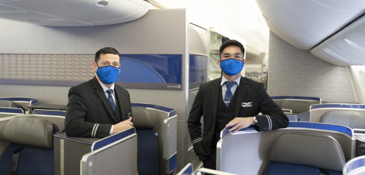 two men wearing face masks in an airplane