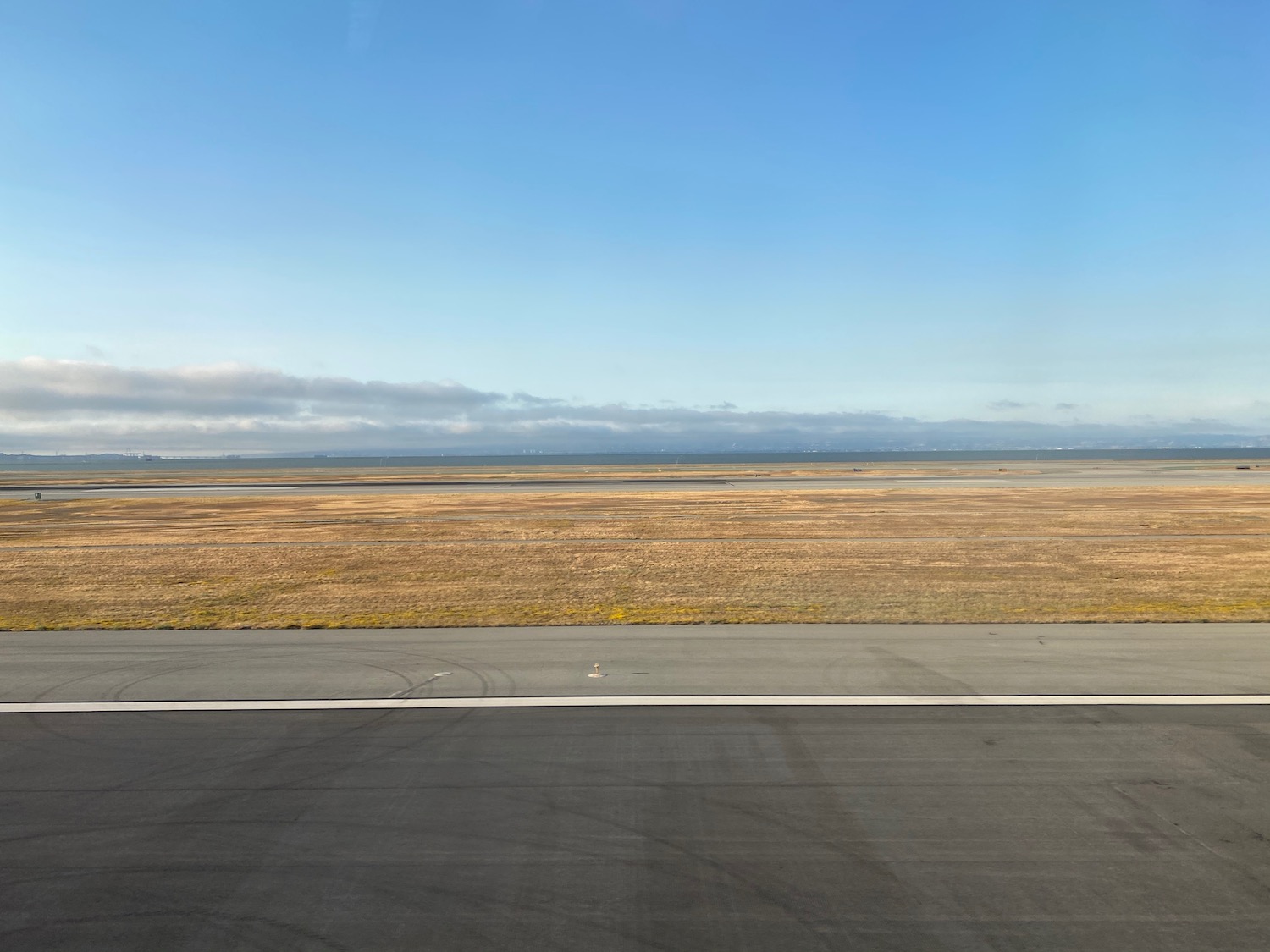 a runway with a field of grass and blue sky