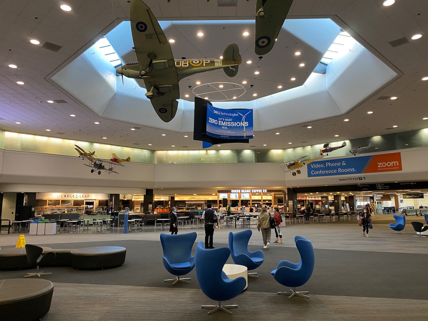 a group of people in a large room with blue chairs and airplanes