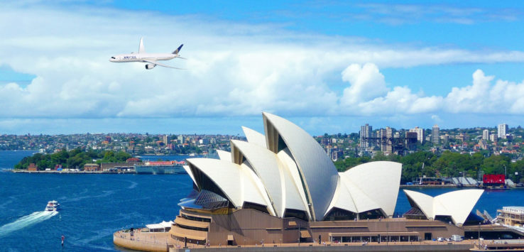 a plane flying over Sydney Opera House