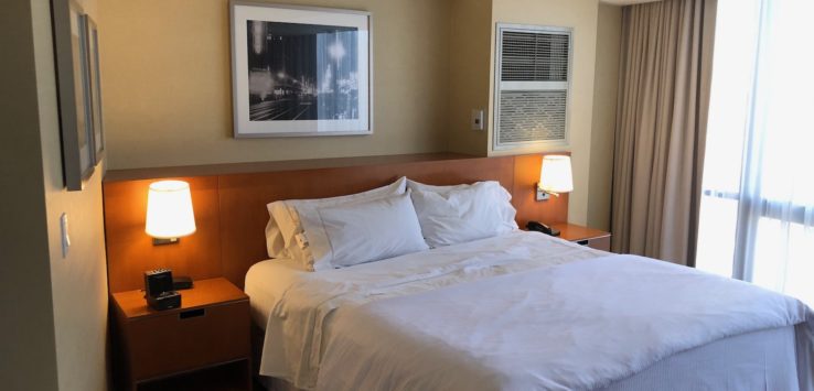 a bed with white sheets and a lamp on the side