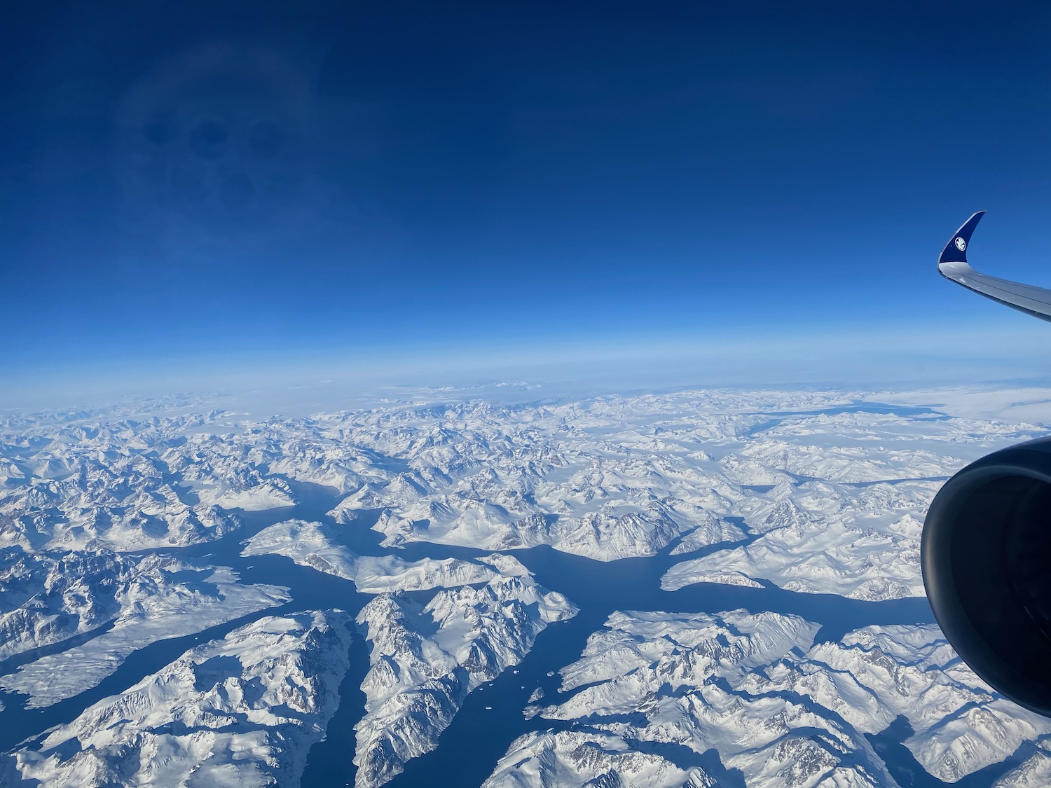 an aerial view of snowy mountains and blue sky