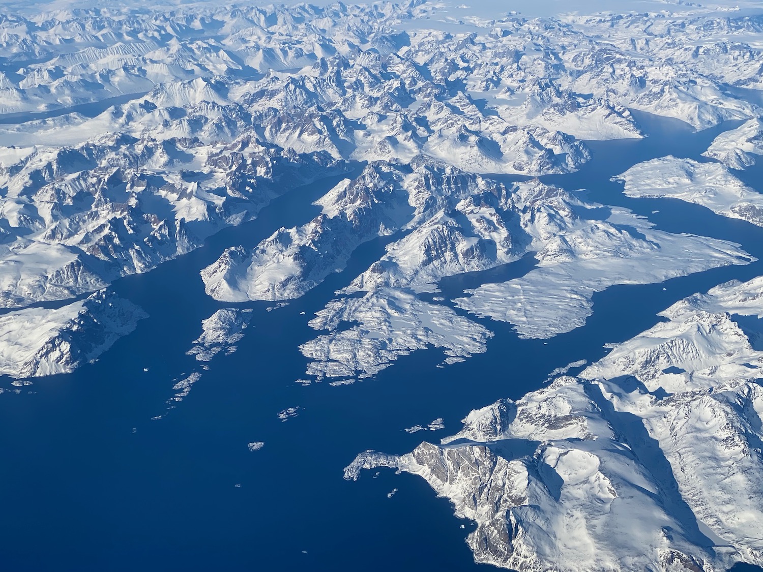 an aerial view of snowy mountains and water
