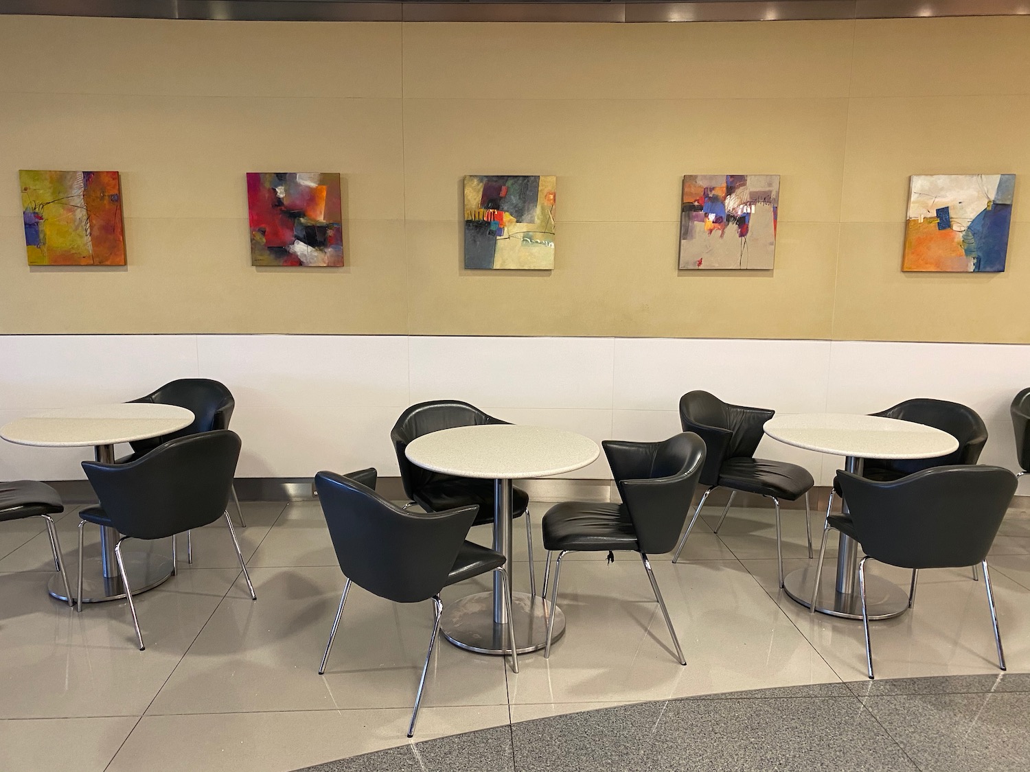 a group of tables and chairs in a room with art on the wall