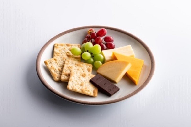 a plate of food with crackers grapes and chocolate