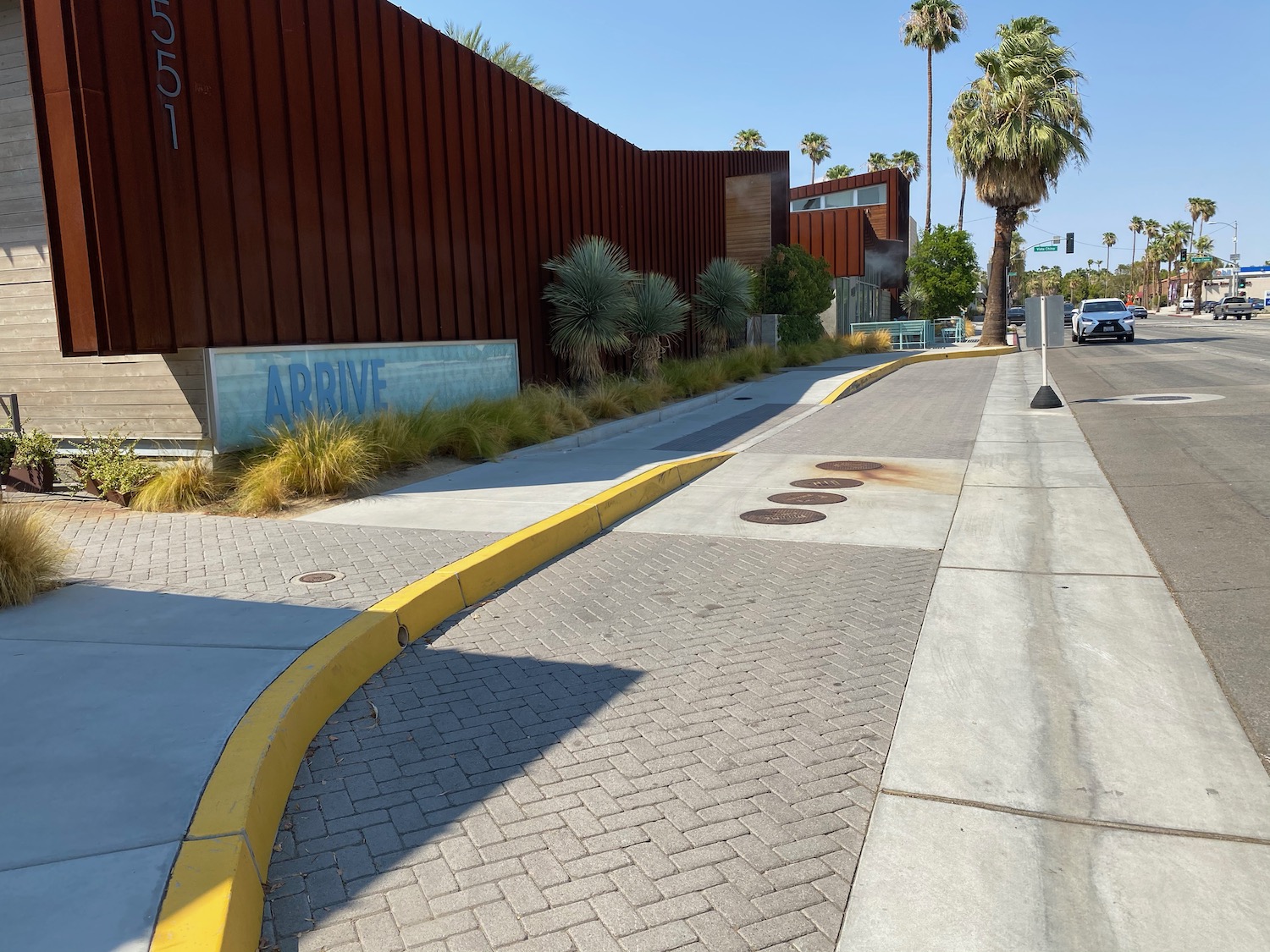 a sidewalk with a building and palm trees