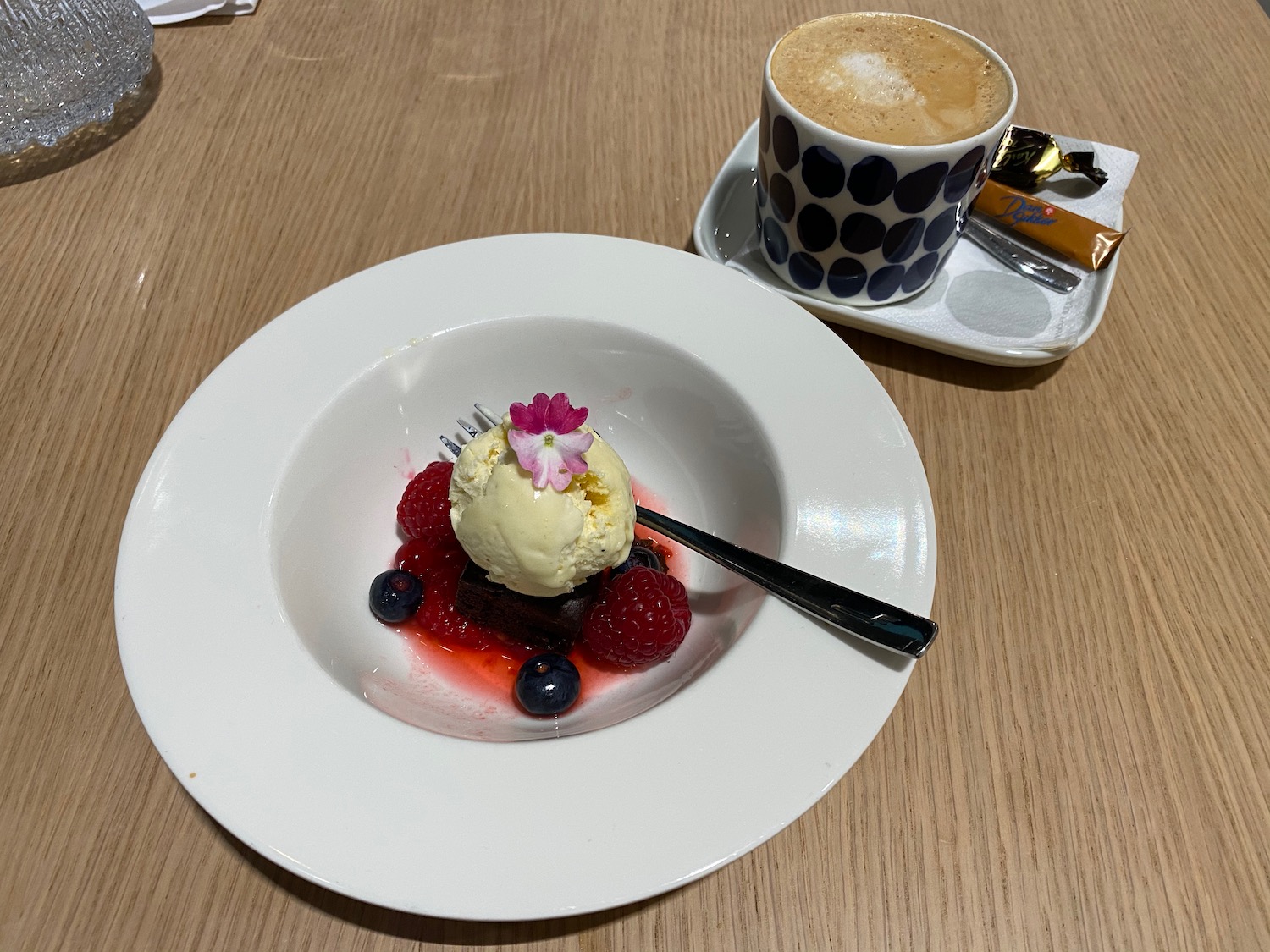 a plate of dessert with a spoon and a cup of coffee