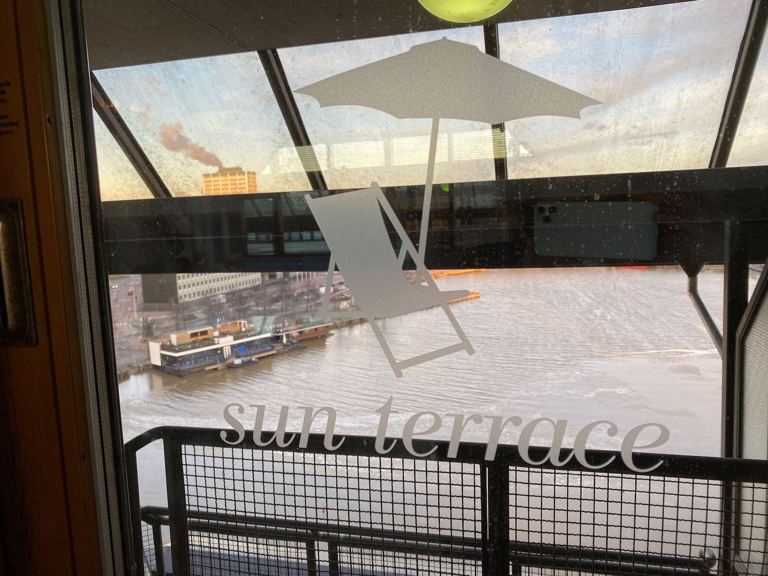 a window with a view of a body of water and a chair and umbrella