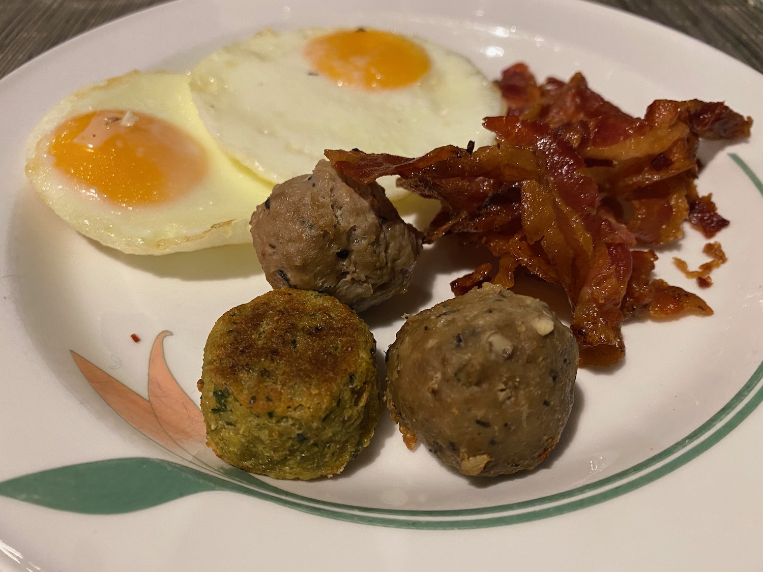 a plate of food with eggs bacon and meatballs