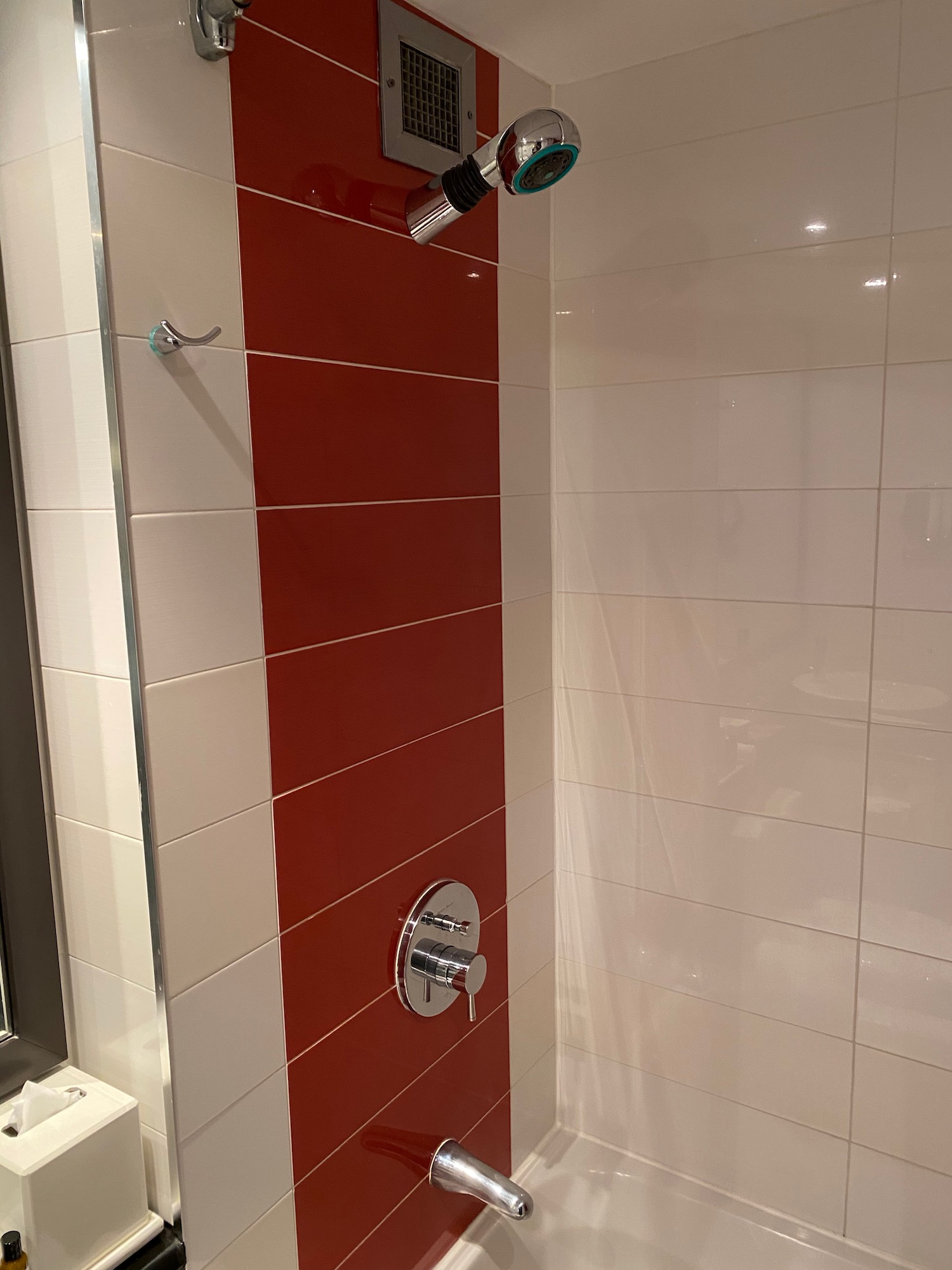 a shower head with a red and white tile wall