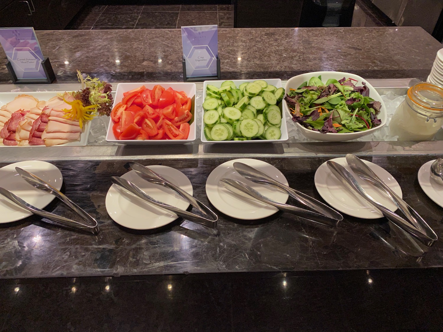 a salad bar with plates of food and utensils