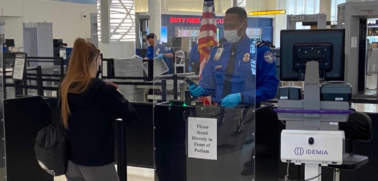 a man wearing a mask and gloves standing behind a glass barrier