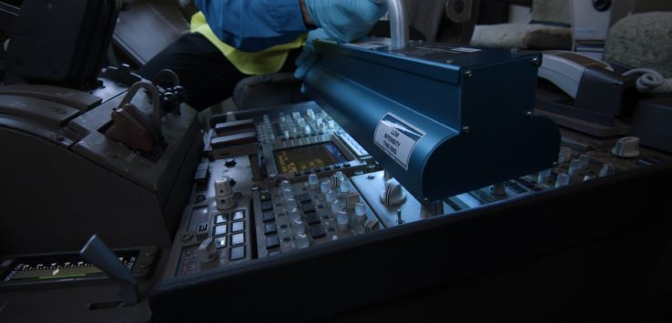 a person in a safety vest and gloves working on a control panel