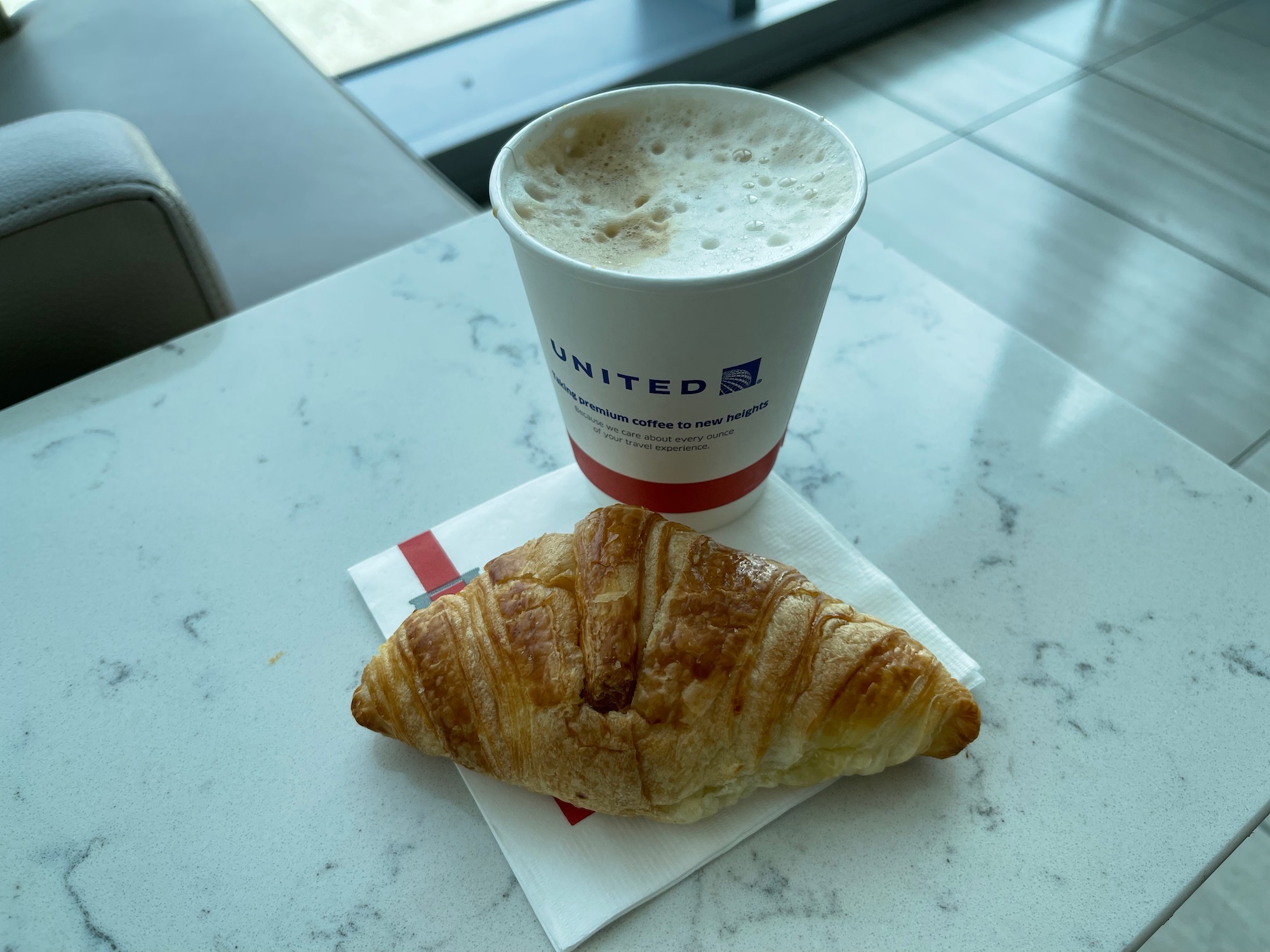 a croissant and a cup of coffee on a table