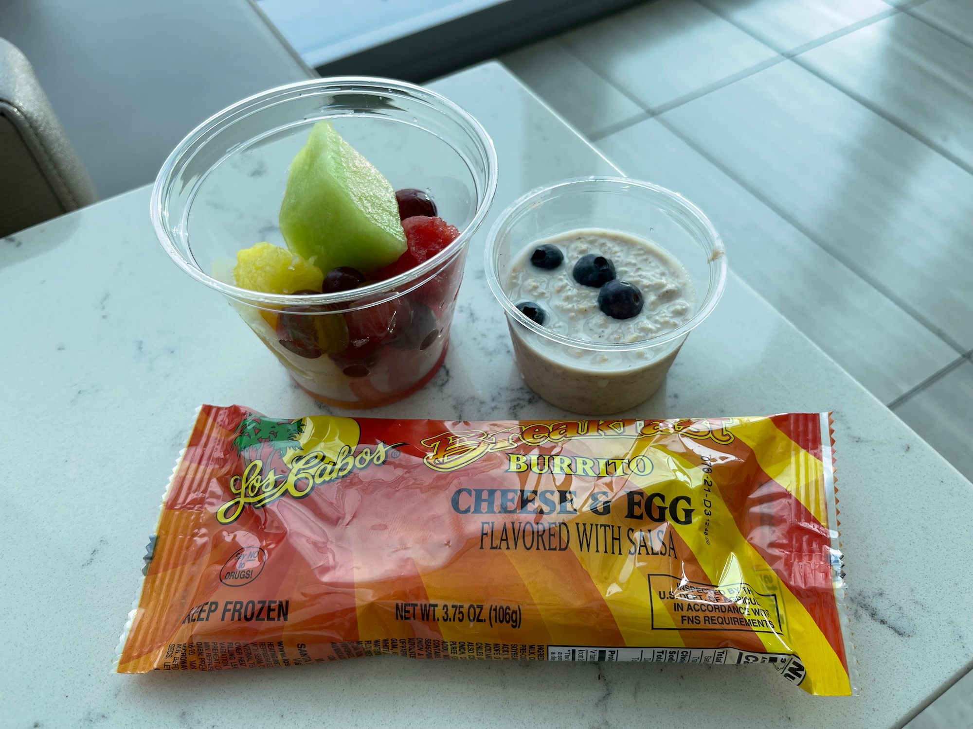 a plastic cups of fruit and a packet of food