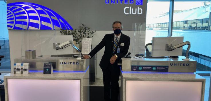 a man wearing a face mask standing in front of a desk