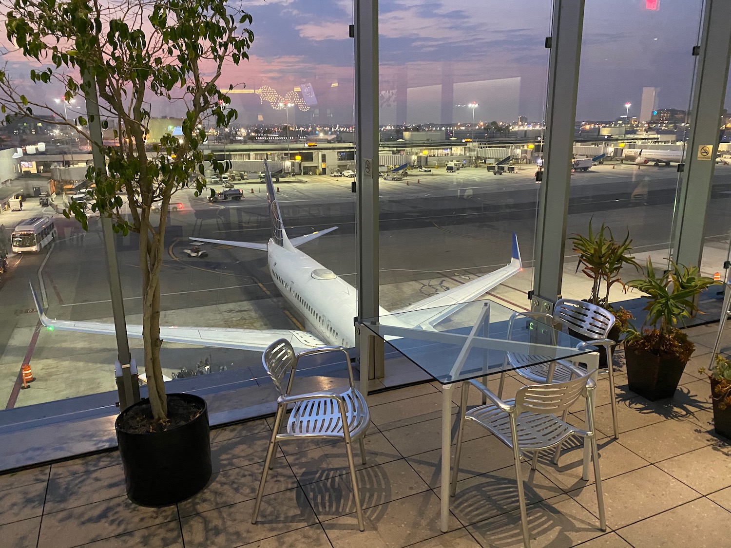 a glass table and chairs in a room with a plane in the background