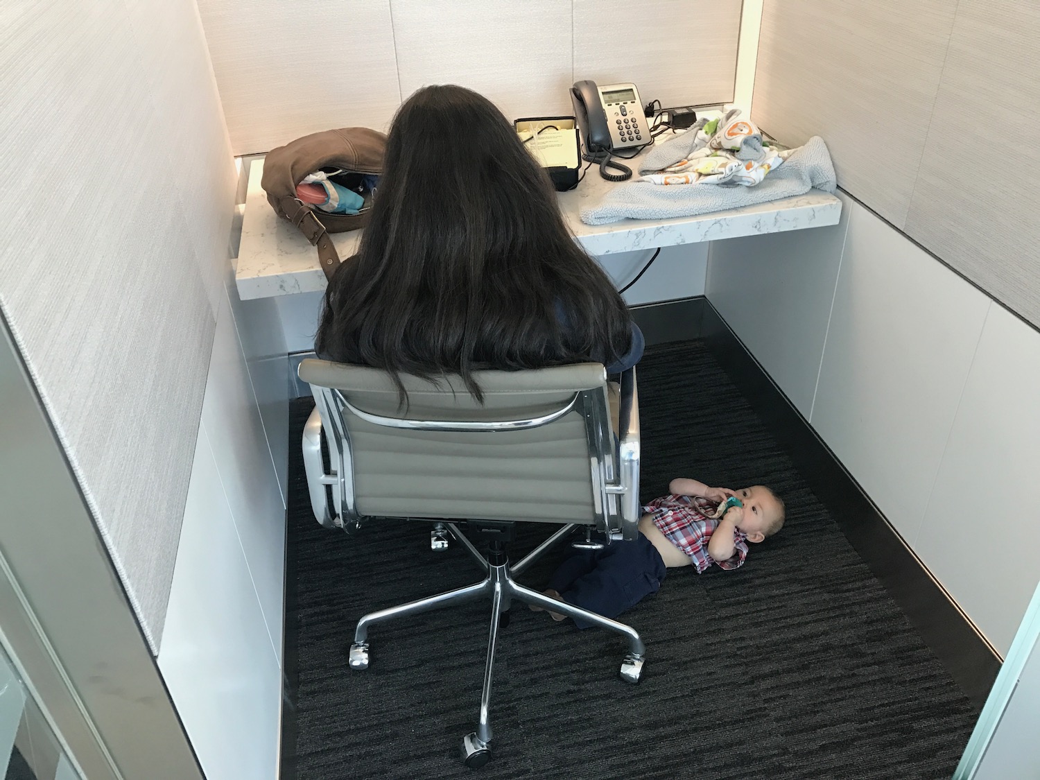 a woman sitting in a chair with a baby lying on the floor