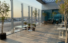 a glass wall with a glass roof and tables and chairs