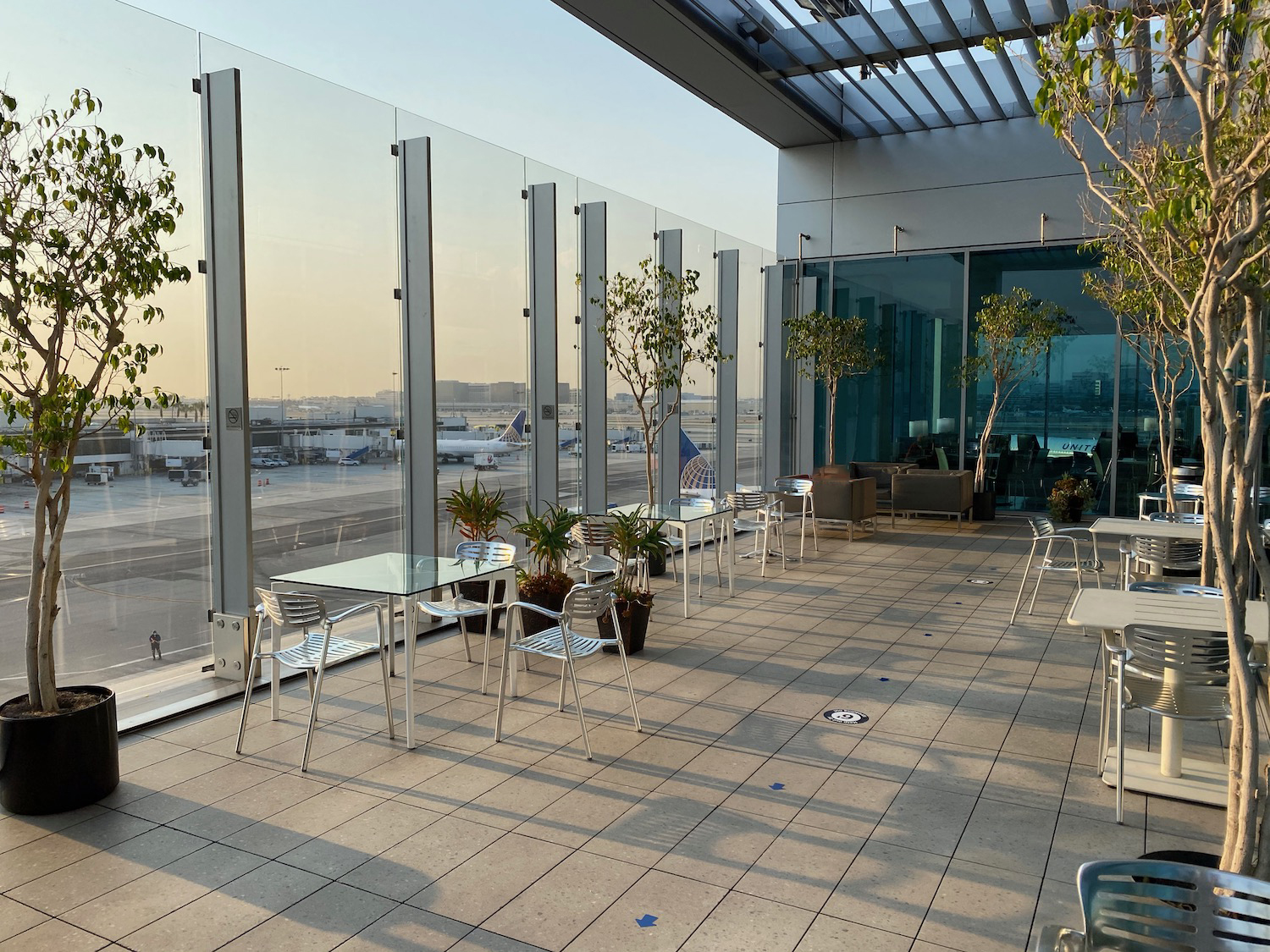 a glass wall with a glass roof and tables and chairs