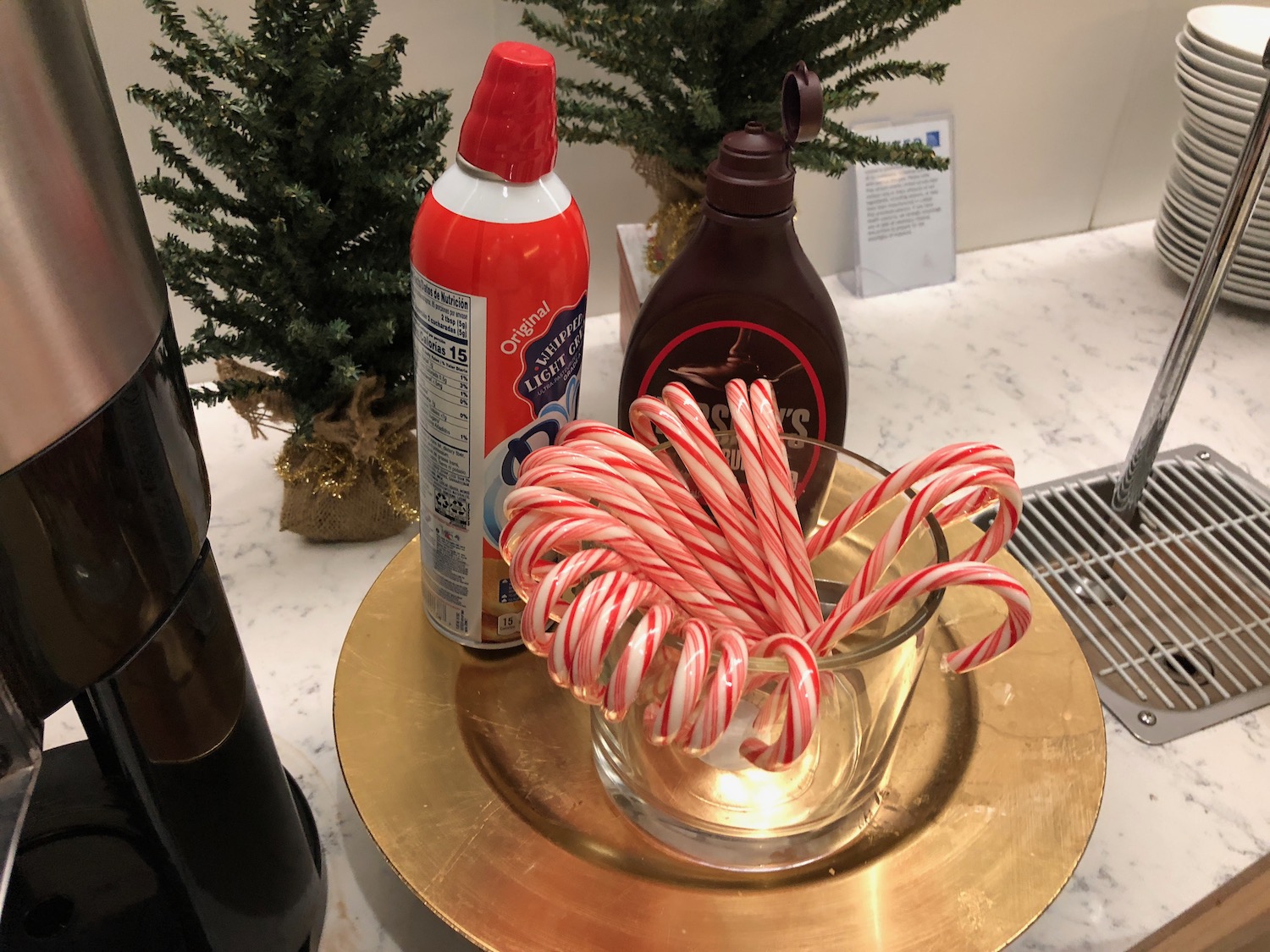 candy canes in a glass cup on a gold plate with a bottle of cleaner