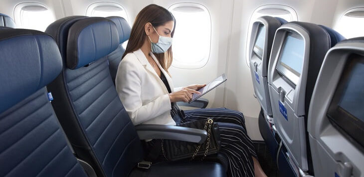 a woman wearing a mask on her face while sitting on an airplane