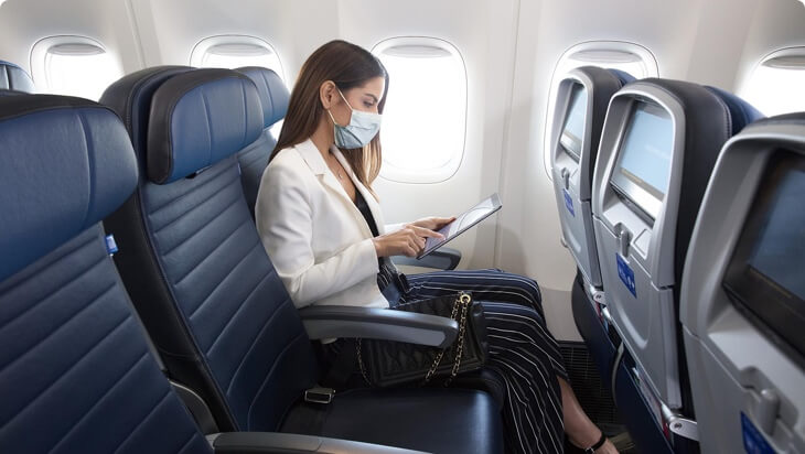 a woman wearing a mask on her face while sitting on an airplane