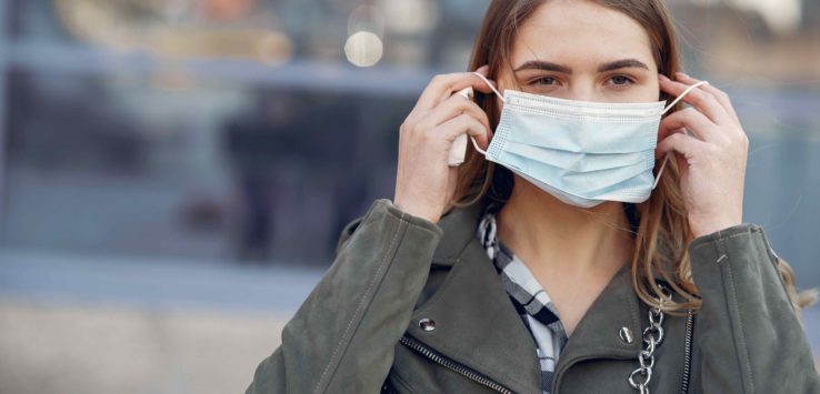 a woman putting on a face mask