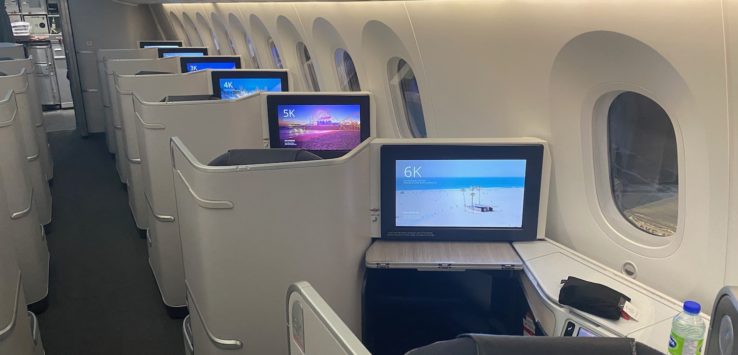 a row of seats with monitors on the side of the plane