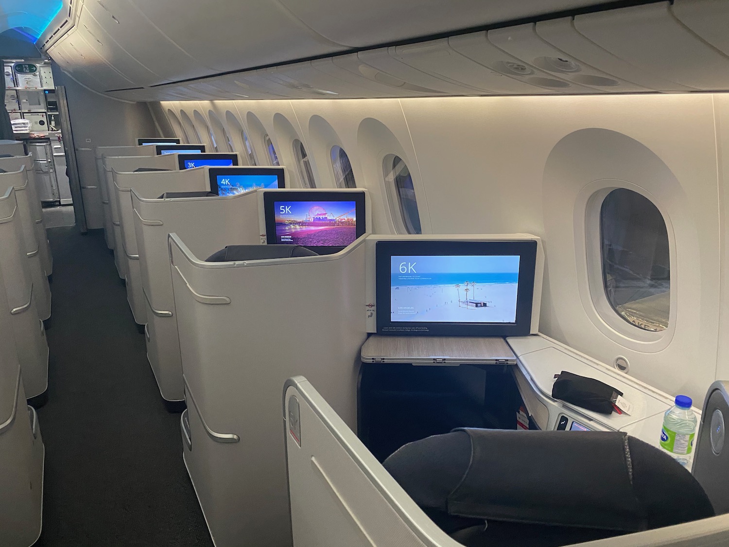 a row of seats with monitors on the side of the plane