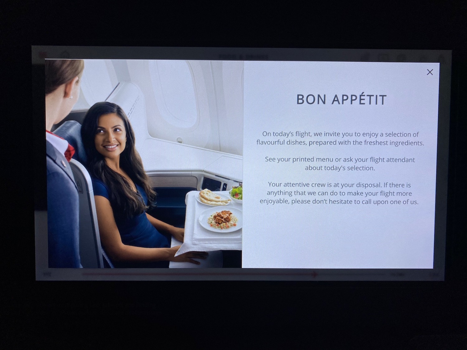 a woman sitting in an airplane with a tray of food