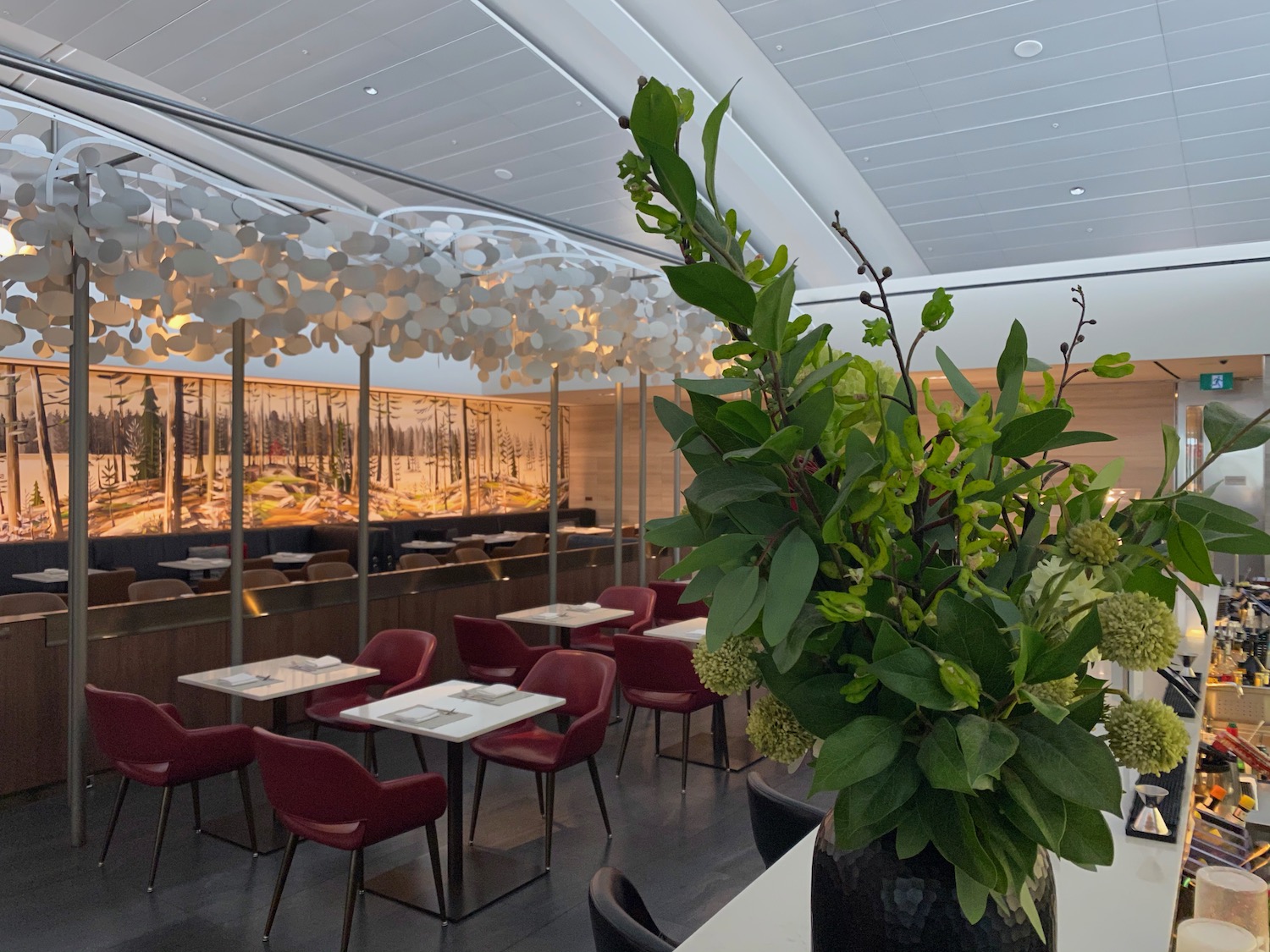 a room with tables and chairs and a vase of green plants