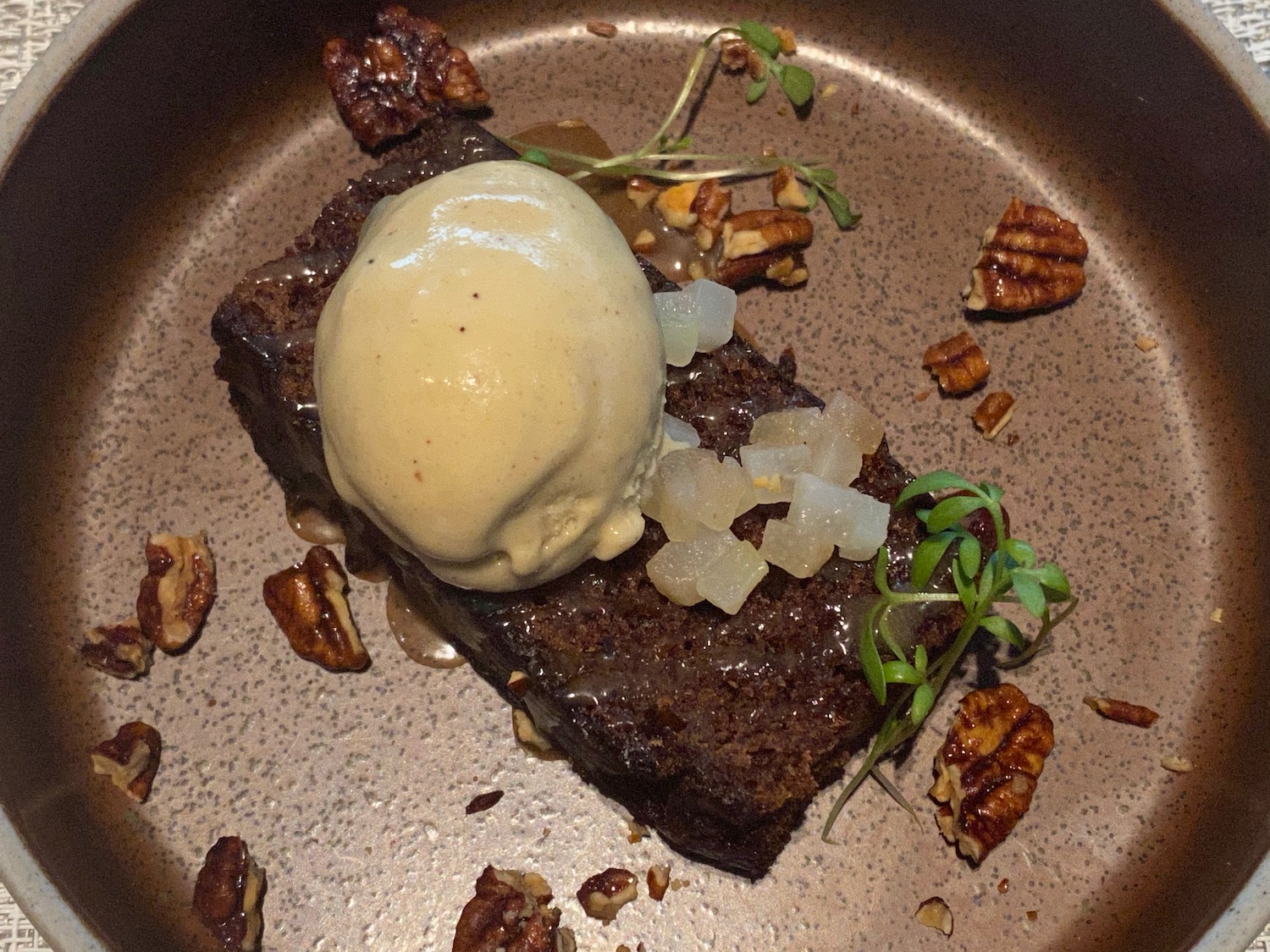 a brownie with ice cream and pecans on a plate