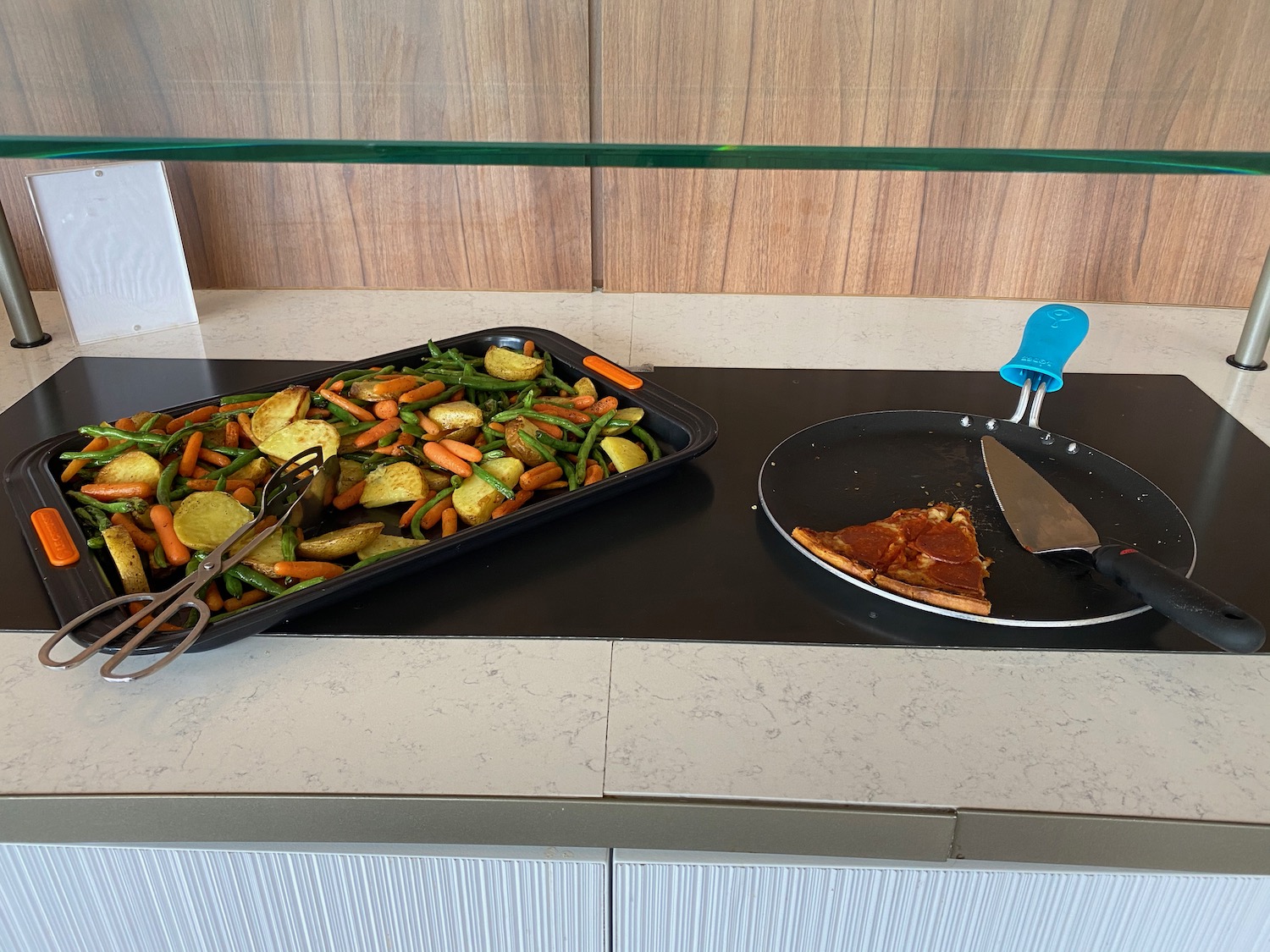 a pans with vegetables and pizza on a counter